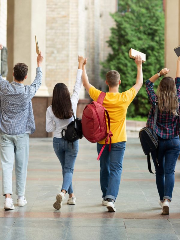 We passed exams. Students raised hands and walking in college campus after the last test
